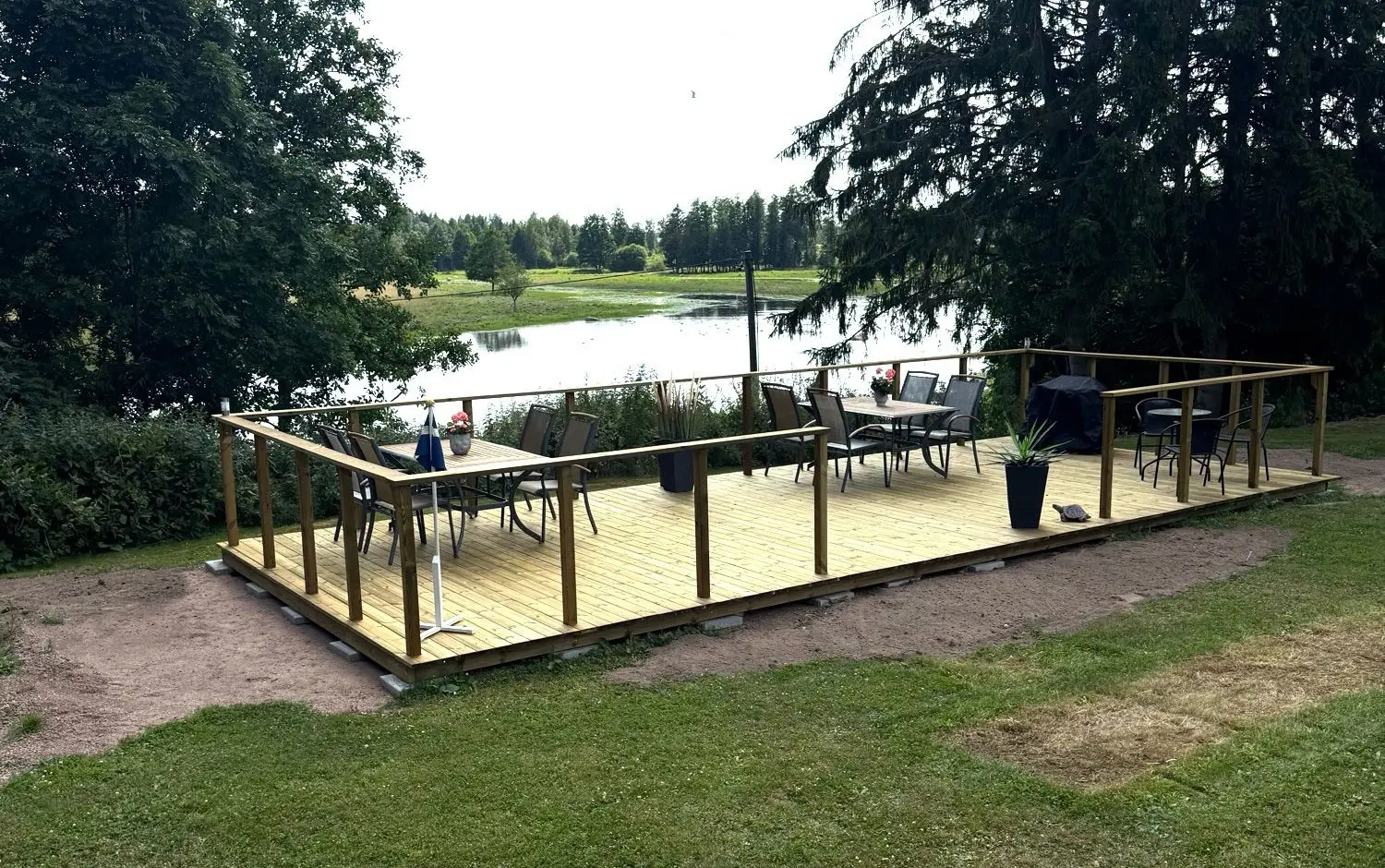 Nybyggt trädäck med bord och stolar framför fågelsjön på Ingelsby Gård Ställplats utanför Tibro